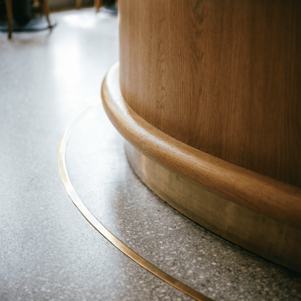 Curved oak counter and brass inlay in a terrazzo floor